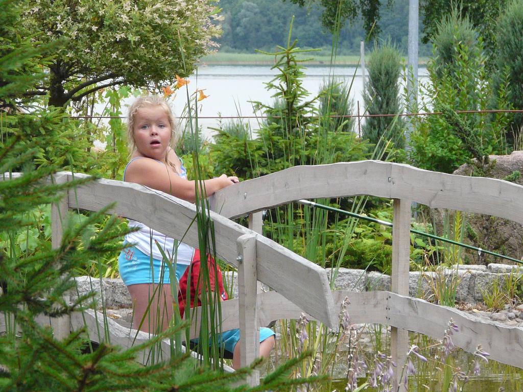 dziewczynka w ogrodzie na mostku oczka wodnego