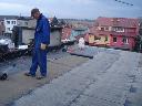 Ocieplenie dachu płaskiego Pracownik firmy podczas wygrzewania papy podk ładowej